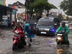 Pengendara motor mendorong motornya yang mogok akibat menerjang banjir di jalan raya Pramuka, Desa Plumbon, Kabupaten Sukoharjo, Jawa Tengah, Sabtu 14 Februari sore. (Foto: Agatha Janendra)