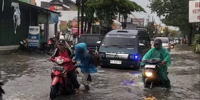Pengendara motor mendorong motornya yang mogok akibat menerjang banjir di jalan raya Pramuka, Desa Plumbon, Kabupaten Sukoharjo, Jawa Tengah, Sabtu 14 Februari sore. (Foto: Agatha Janendra)