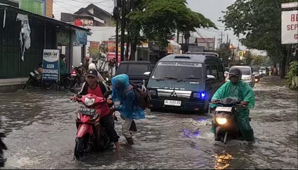 Pengendara motor mendorong motornya yang mogok akibat menerjang banjir di jalan raya Pramuka, Desa Plumbon, Kabupaten Sukoharjo, Jawa Tengah, Sabtu 14 Februari sore. (Foto: Agatha Janendra)