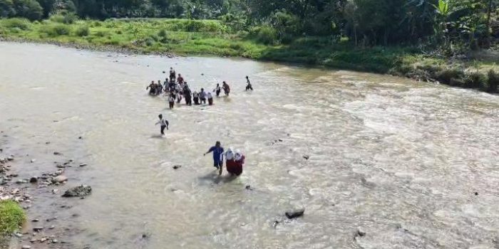 Warga mengantar anak-anaknya berangkat ke sekolah berjalan kaki dengan menyeberangi Sungai Serang di Desa Bolo, Kecamatan Wonosegoro, Kabupaten Boyolali, Jawa Tengah. (Foto: Agatha Janendra)